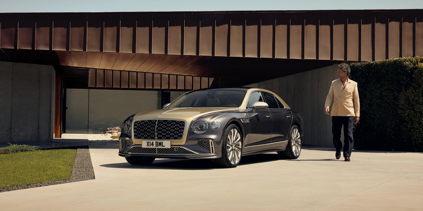 Bentley Monterrey Bentley New Flying Spur Mulliner V8 hybrid sedan front three quarters in Rose Gold over Magnetic paint, parked near modern home