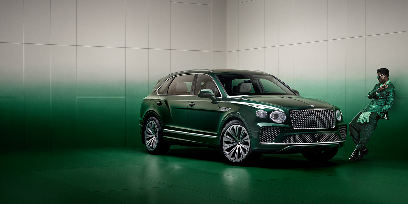 Bentley Monterrey Wisdom K leans against wall next to Bentley Bentayga Extended Wheelbase Atelier Edition SUV in Light Emerald green paint