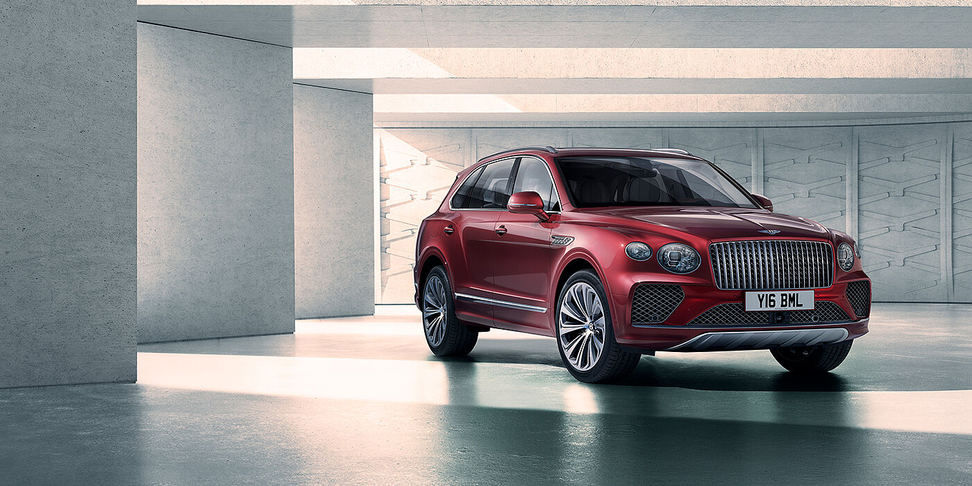 Bentley Monterrey Bentley Bentayga Atelier Edition SUV in Rubino Red paint front three quarter against textured concrete wall
