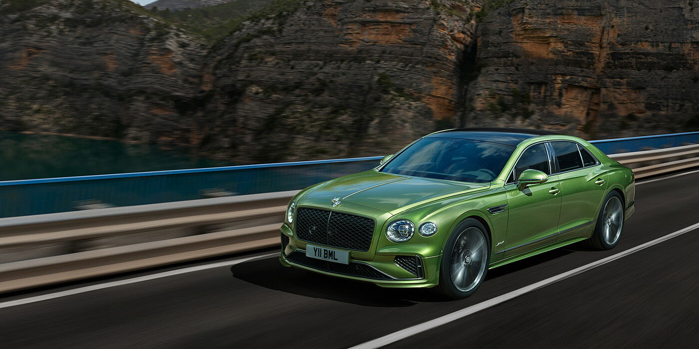 Bentley Monterrey Bentley New Flying Spur Speed v8 hybrid sedan driving dynamically on a mountain road in Tourmaline Green paint