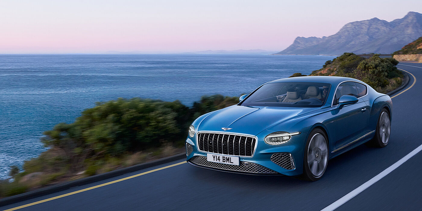 Bentley Monterrey New Bentley Continental GT Azure coupe in Light Windsor blue paint with 22 inch Azure wheels and chrome grill, driving dynamically by the sea